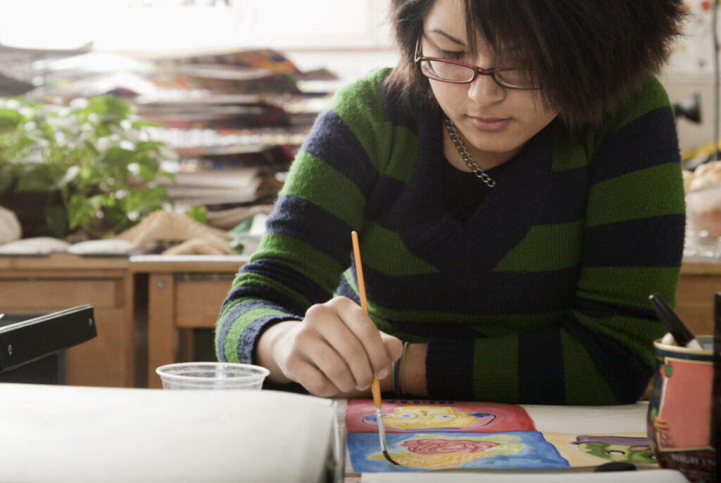 Hispanic teen painting with a calm expression