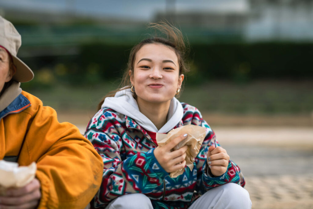 Niña adolescente al aire libre comiendo una merienda y sonriendo