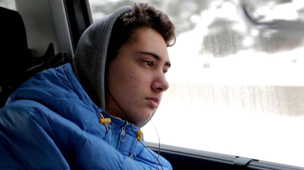 Depressed teenage boy looking out a car window
